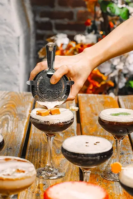 Bartender straining an espresso martini into a coupe glass